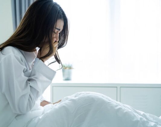 Woman seated in bed with nausea