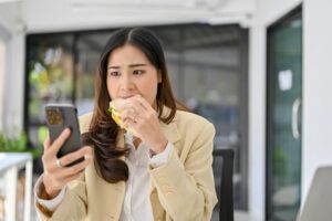 Asian women eating while using her phone