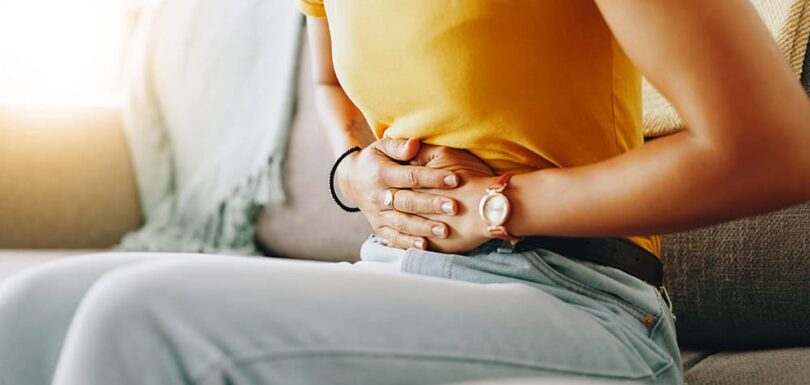 Woman experiencing upper abdominal stomach pain, representing gastritis symptoms