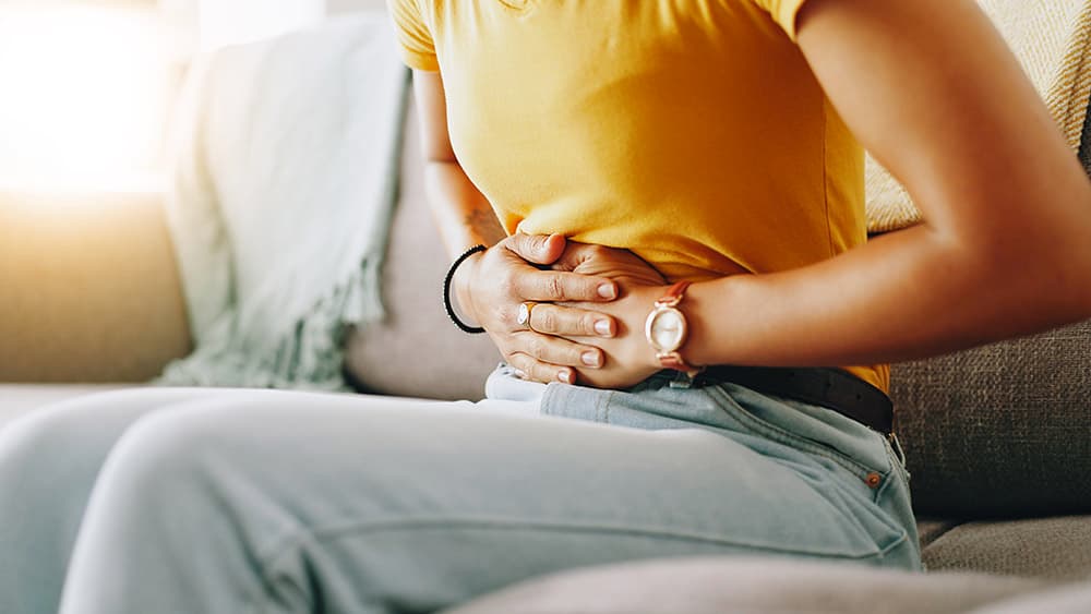 Woman experiencing upper abdominal stomach pain, representing gastritis symptoms